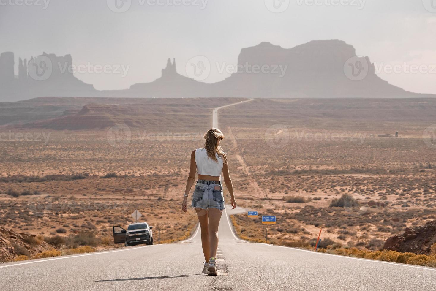 achterzijde visie van vrouw wandelen Aan weg leidend naar monument vallei gedurende zomer foto