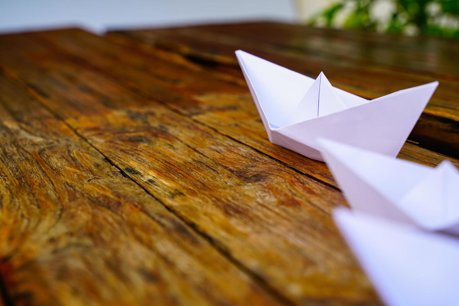 origami, wit papier boot geïsoleerd Aan een houten vloer. papier boten gemeen wandelen. gevoel van vrijheid leiderschap foto