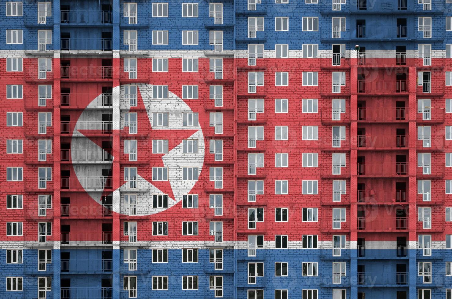 noorden Korea vlag afgebeeld in verf kleuren Aan meerdere verdiepingen woonachtig gebouw onder bouw. getextureerde banier Aan steen muur achtergrond foto