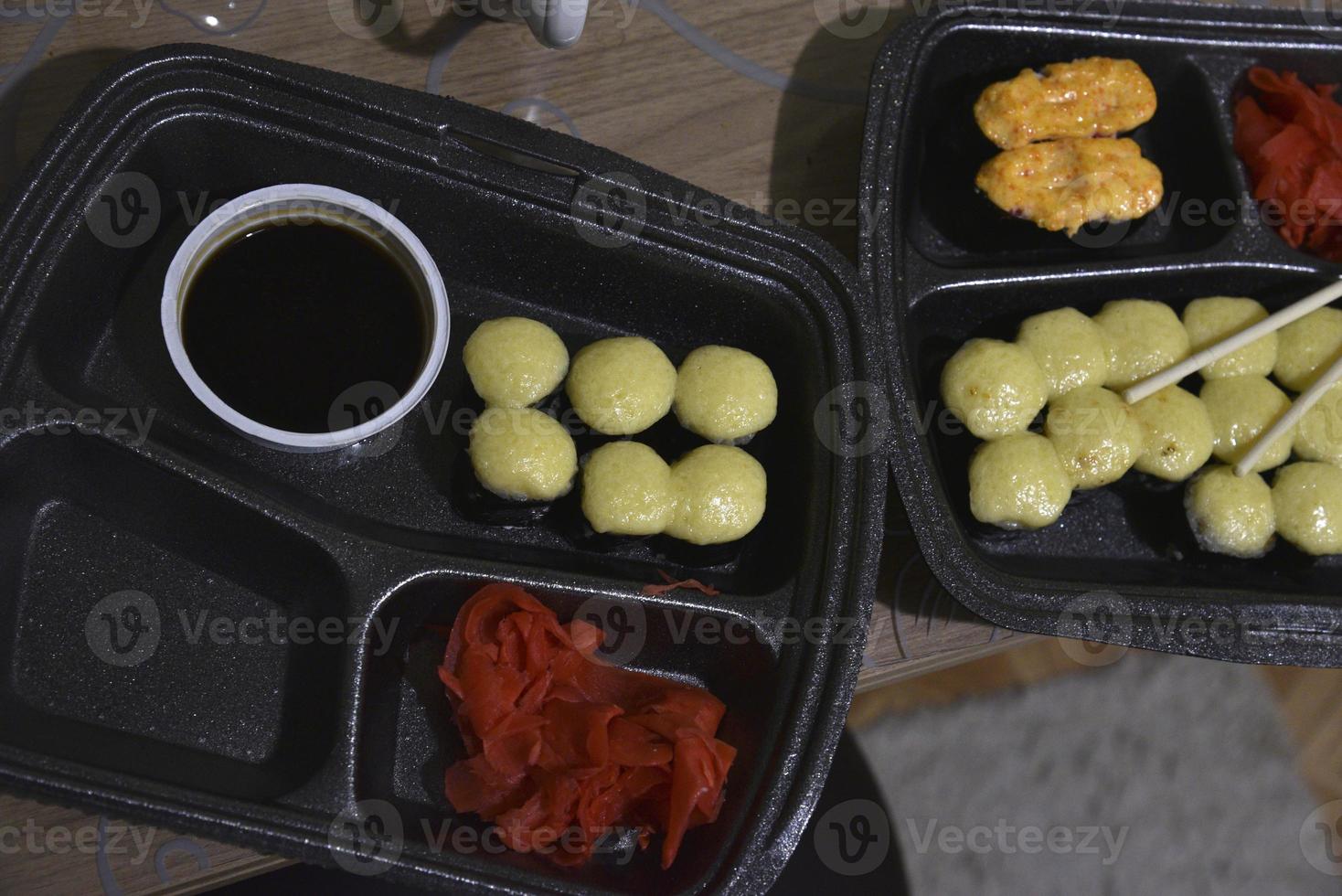 gebakken sushi en broodjes in plastic containers met eetstokjes. Japans keuken. een heerlijk tussendoortje. foto