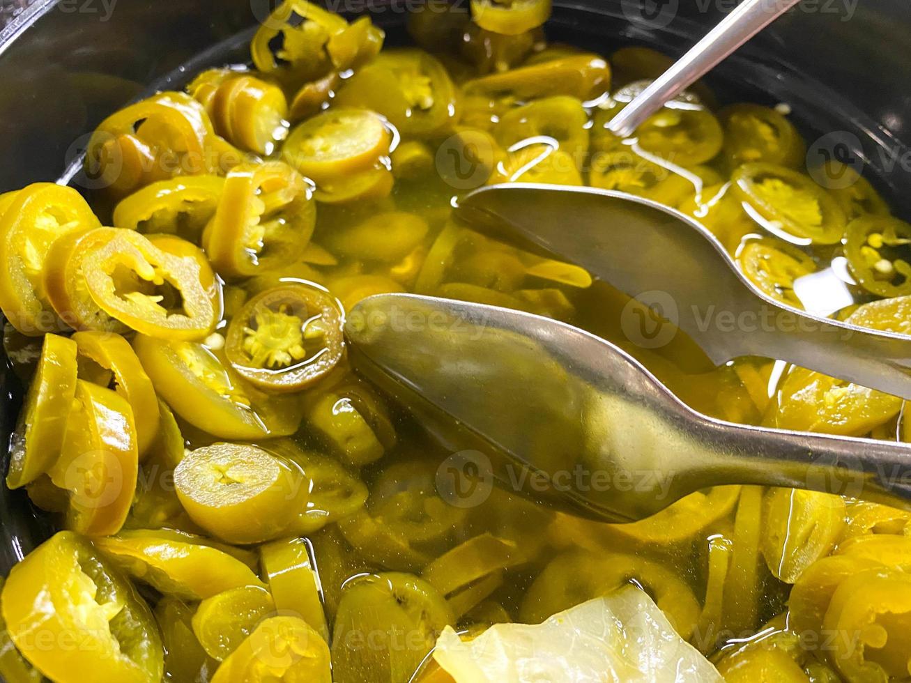 heerlijk groen natuurlijk vers gepekeld gezond tomaten besnoeiing in plakjes in een bord met tang foto