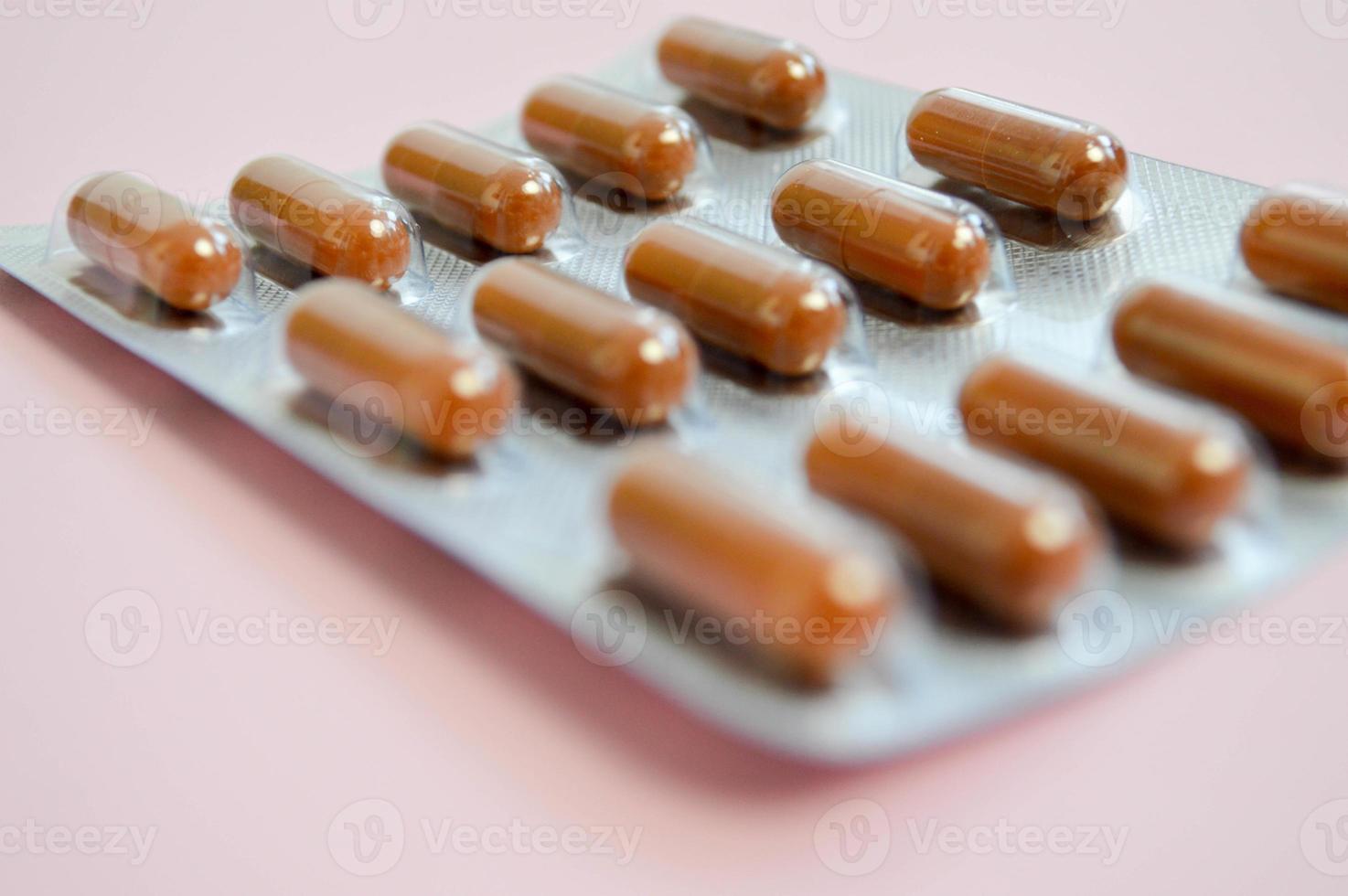 medisch farmaceutisch bruin medicijnen voor de behandeling van ziekten en de doden van microben en virussen tablets en vitamines blaren blaren van coronavirus covid-19 Aan een roze achtergrond foto