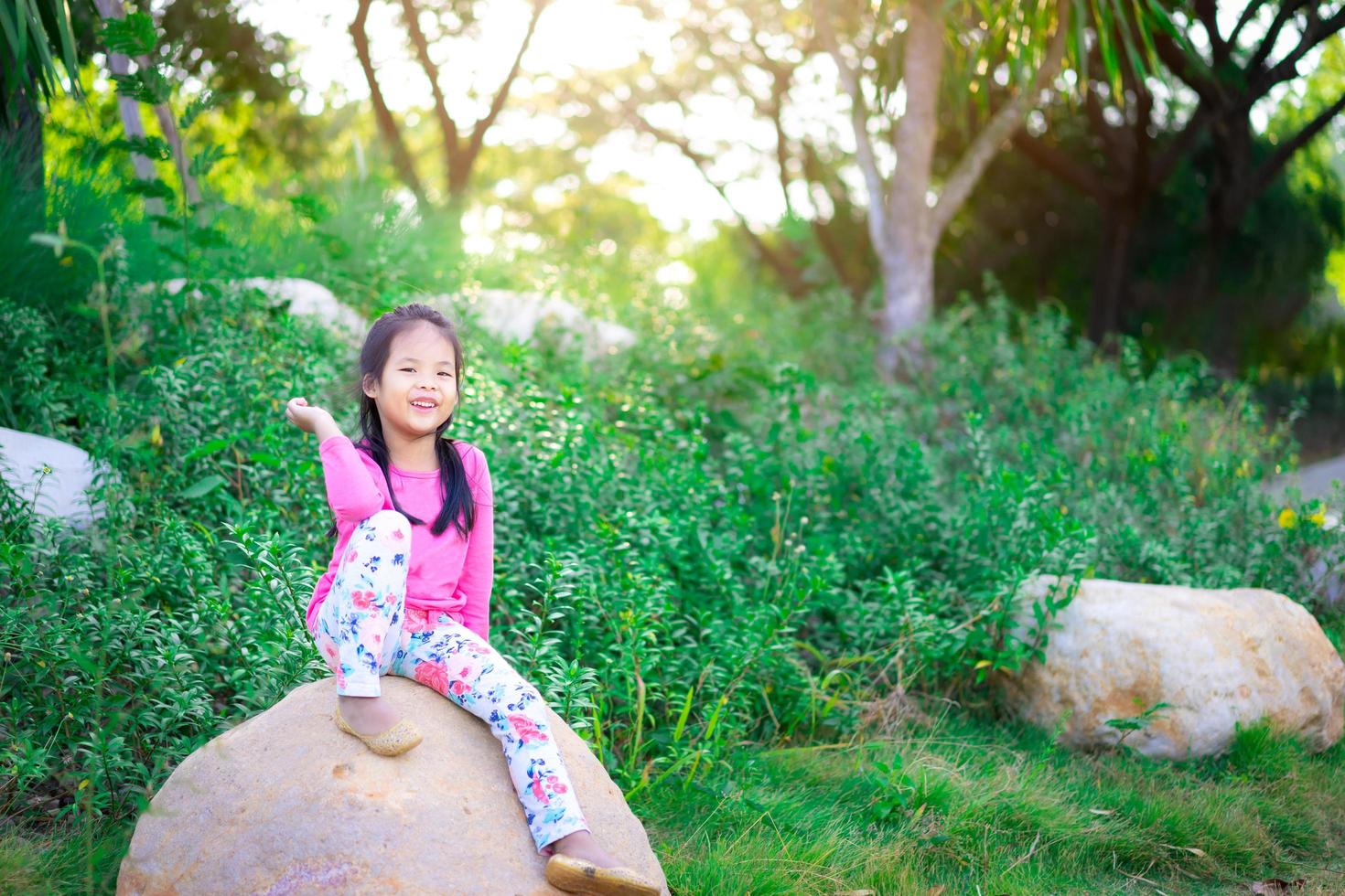 gelukkig Aziatisch meisje zittend op de rots met zonlicht foto