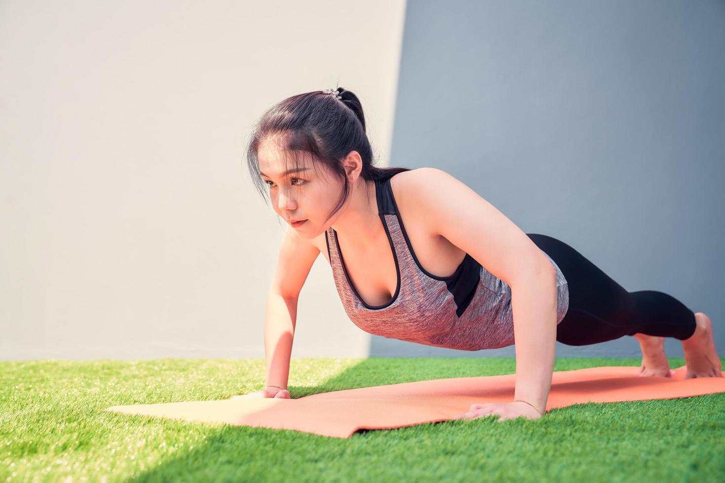 vrouw oefenen push-ups op een trainingsmat buiten foto