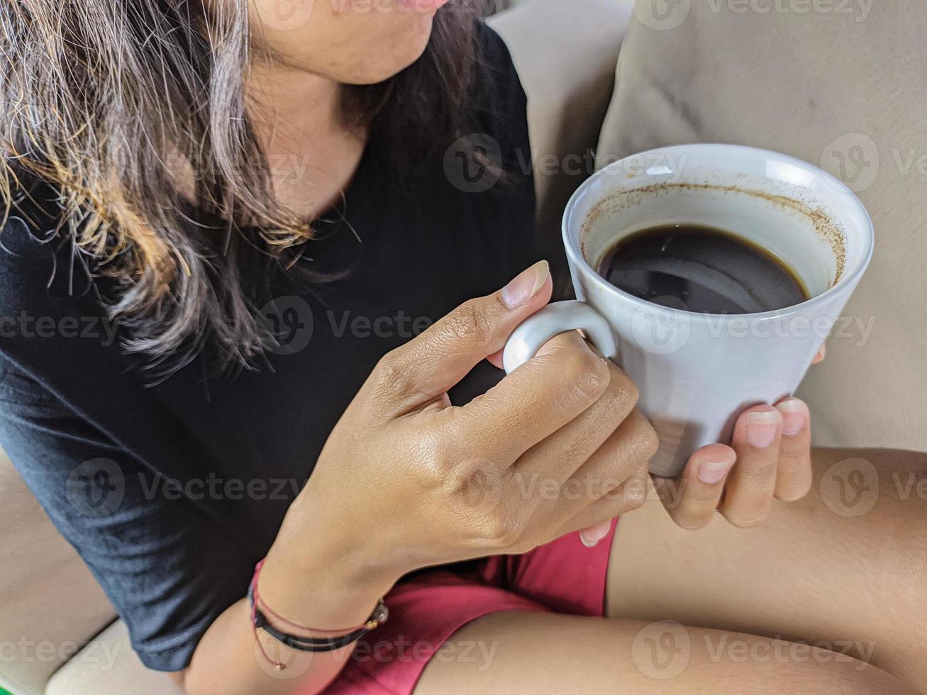 een jong vrouw dronken een glas van koffie Aan de sofa terwijl ontspannend. Kerstmis en nieuw jaar vakantie foto