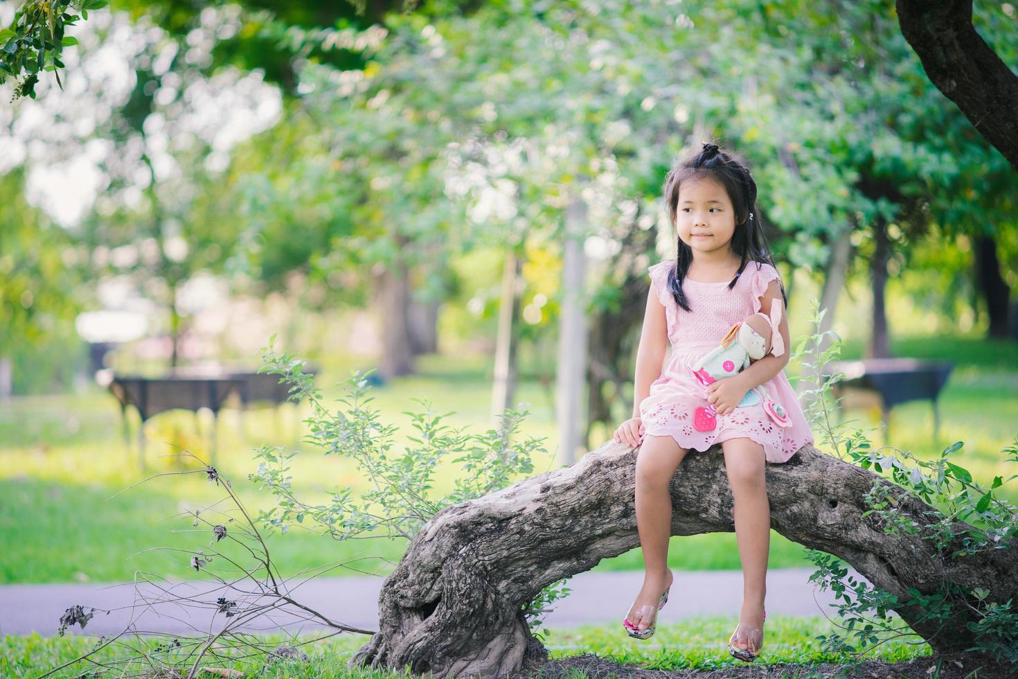 Aziatisch meisje met een pop in het park zitten foto