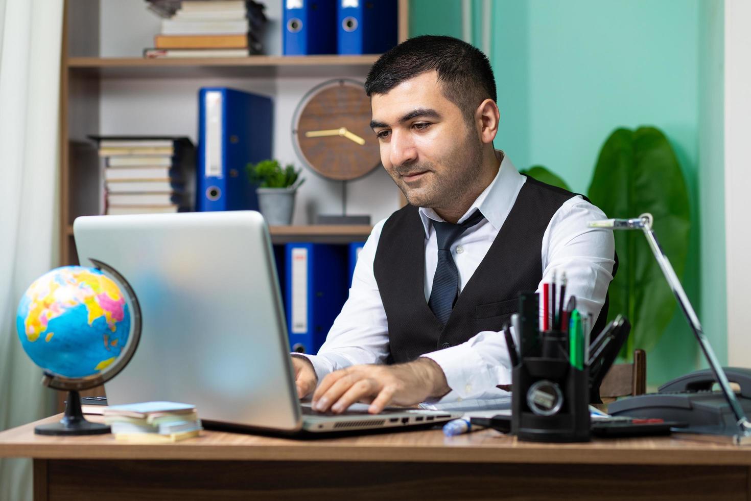 jonge zakenman aan het werk op laptop aan tafel foto