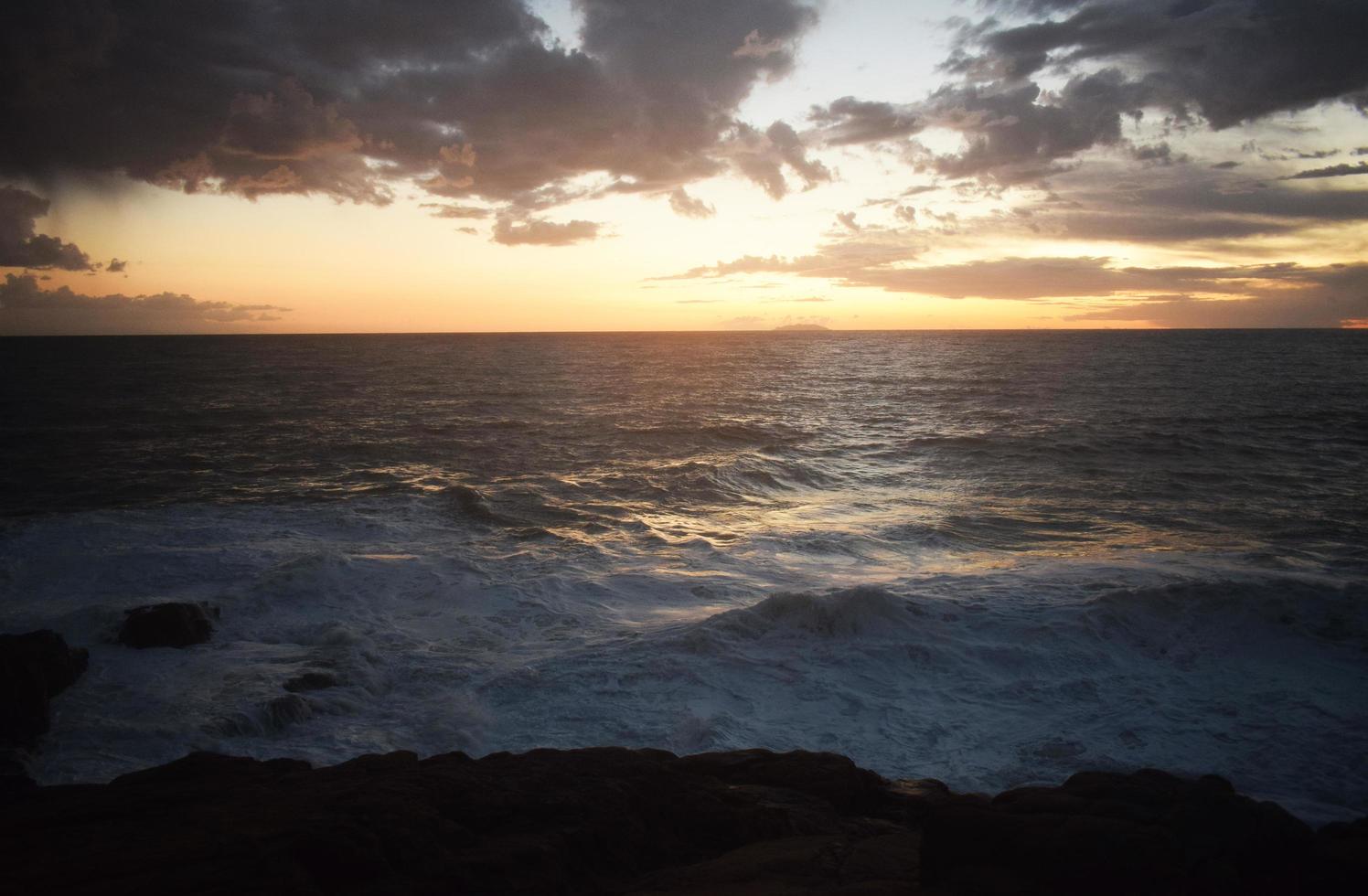 oceaangolven die tijdens zonsondergang op rotsen breken foto