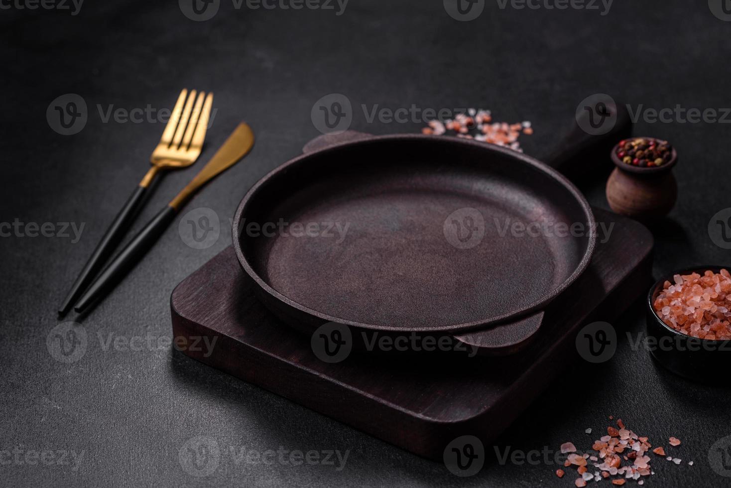 bruin ijzer leeg pan met keuken gereedschap Aan een donker beton achtergrond foto