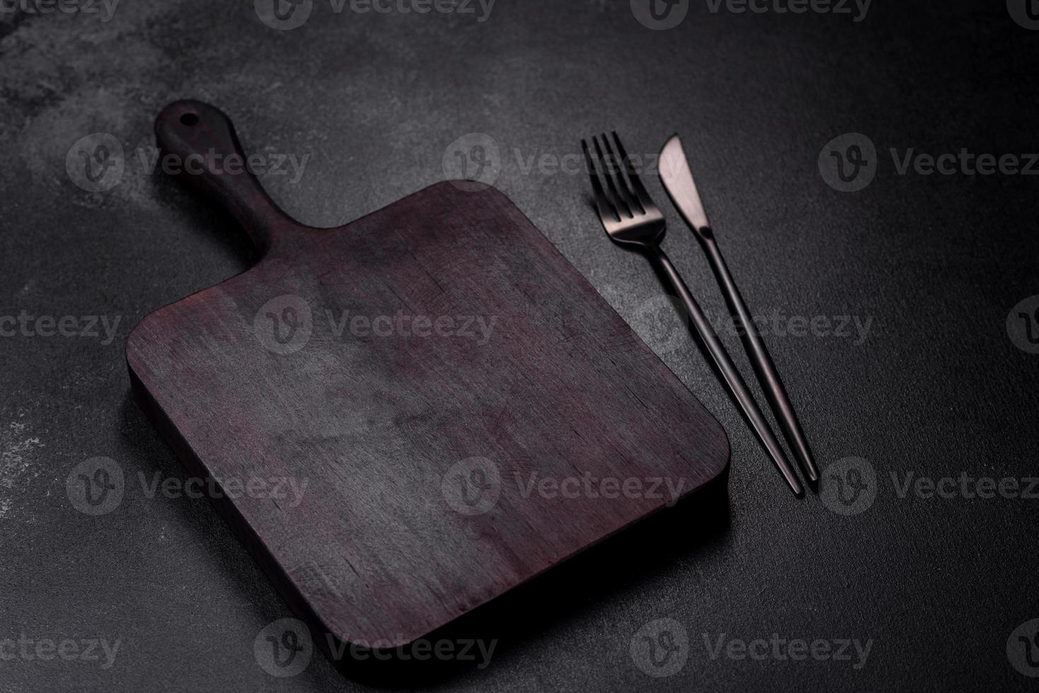houten snijdend bord met keuken huishoudelijke apparaten Aan een zwart beton achtergrond foto