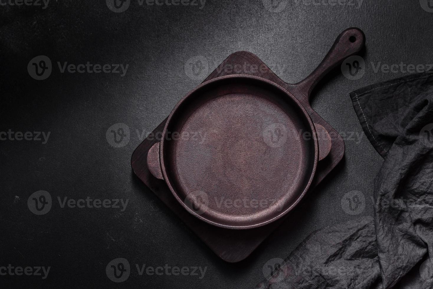 bruin ijzer leeg pan met keuken gereedschap Aan een donker beton achtergrond foto