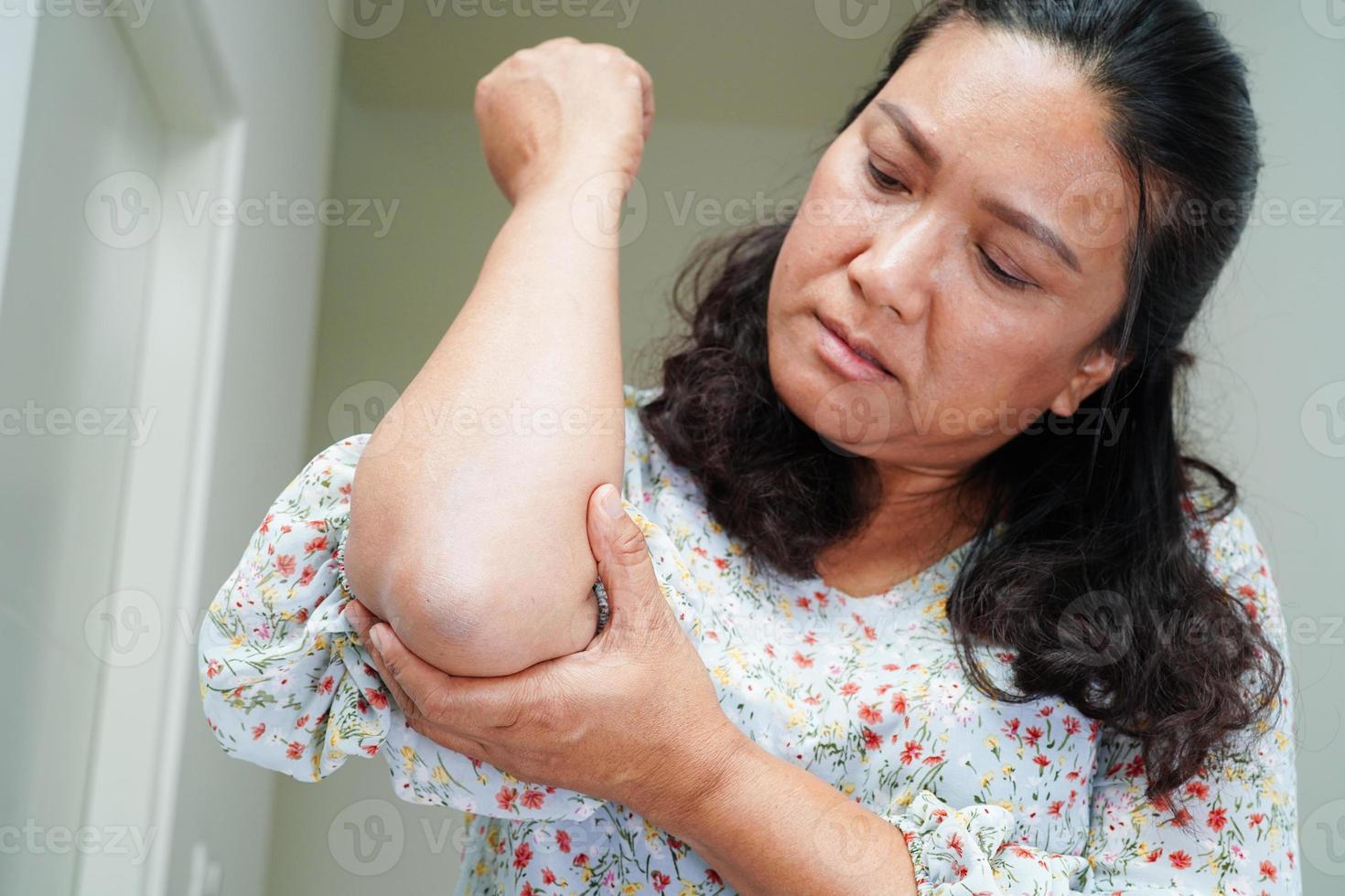 aziatische senior vrouw die elastische steun elleboogbrace draagt om pijn te verminderen. foto