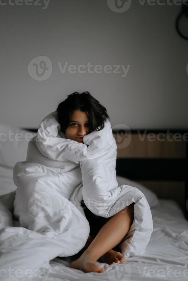 lui vrouw verpakt in zacht deken zittend in knus bed foto