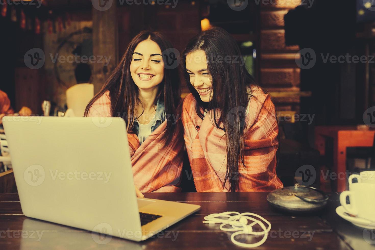 twee meisjes kijken naar iets in de laptop foto