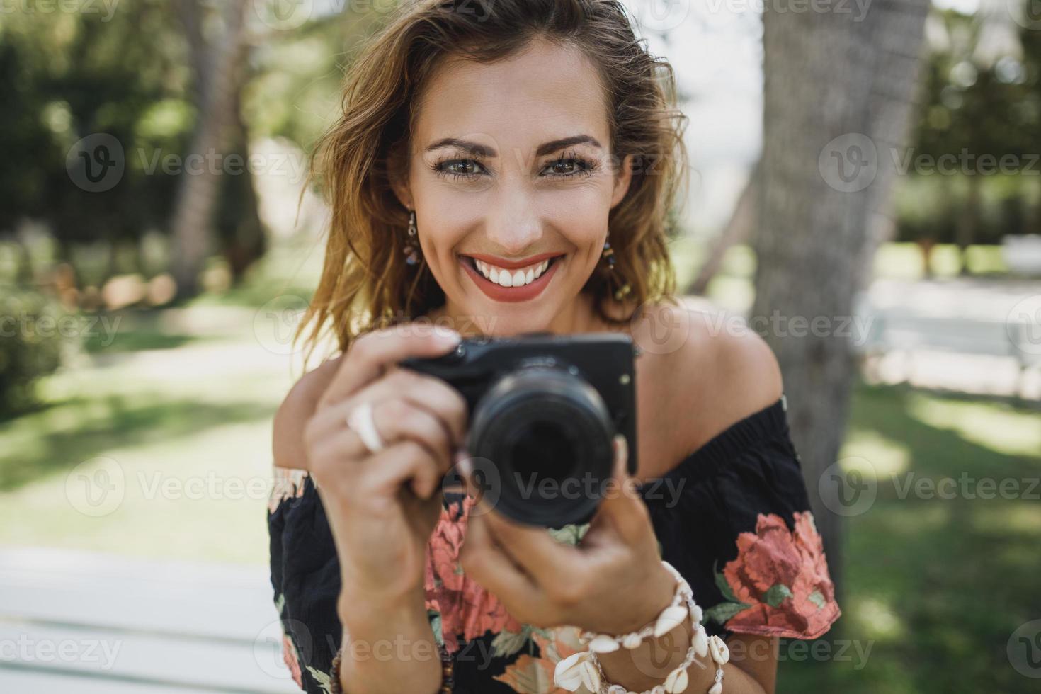portret van een vrouw met digitaal camera glimlachen en op zoek Bij camera foto