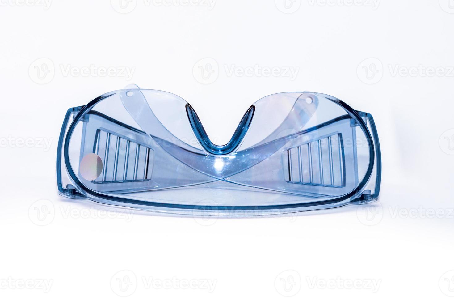 blauw plastic veiligheid bril Aan een wit achtergrond geïsoleerd, dichtbij -omhoog. concept van beroeps Gezondheid en veiligheid foto