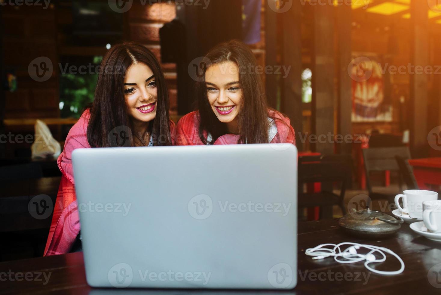 twee meisjes kijken naar iets in de laptop foto