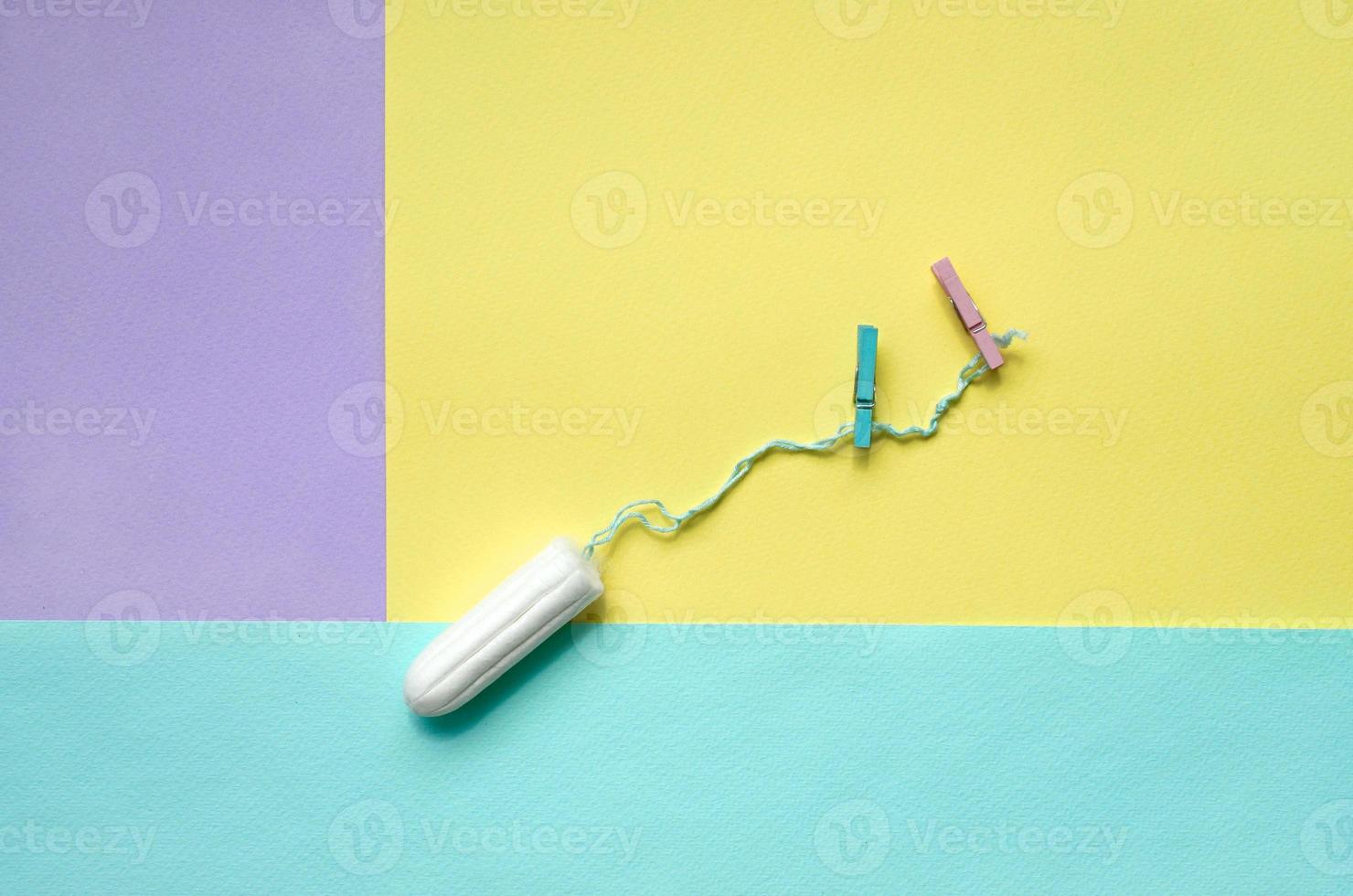 tampon met twee wasknijpers liggen Aan structuur achtergrond van mode pastel paars, geel en blauw kleuren papier in minimaal concept foto