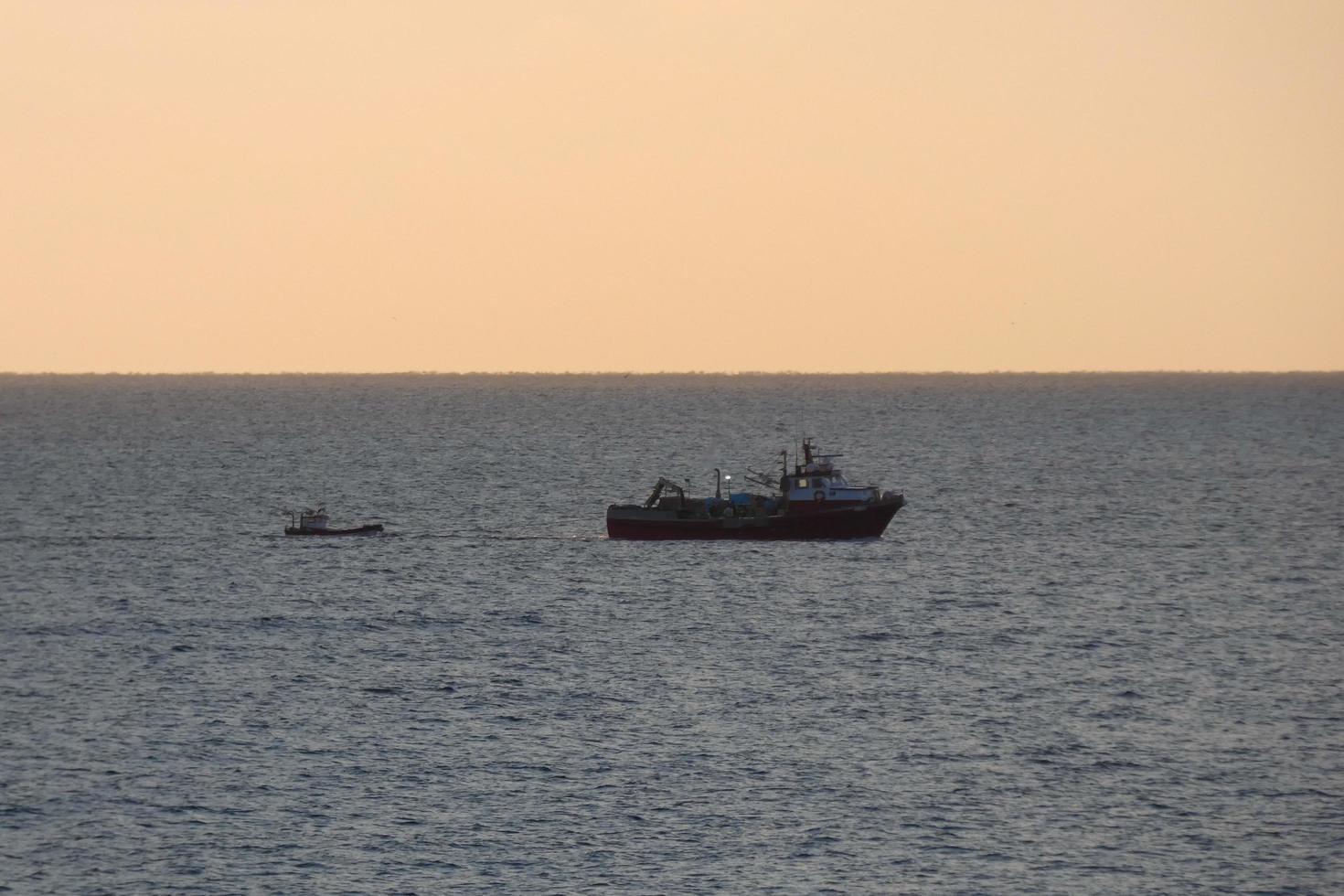 vissers terugkeren van visvangst Bij dageraad na uitgeven de geheel nacht Bij zee. foto