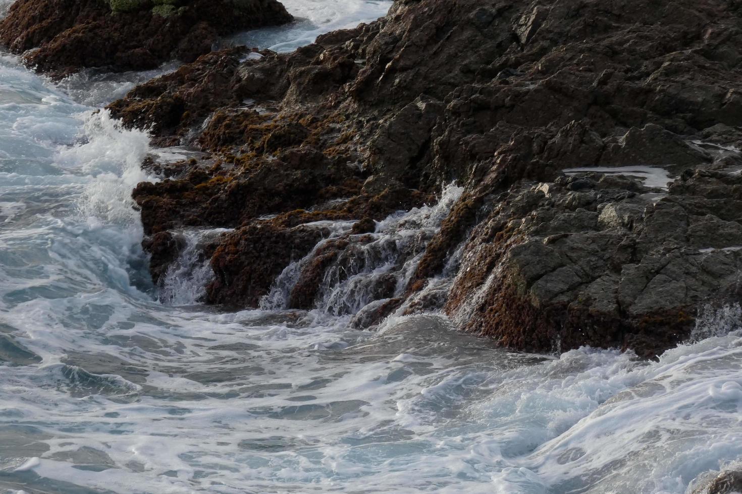 zee bereiken de rotsen creëren spatten van schuim foto