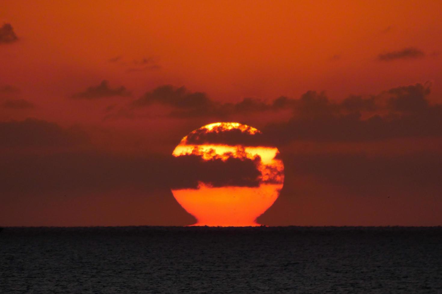 zon schijf stijgende lijn over- de horizon van de zee, zonsopkomst, dageraad foto