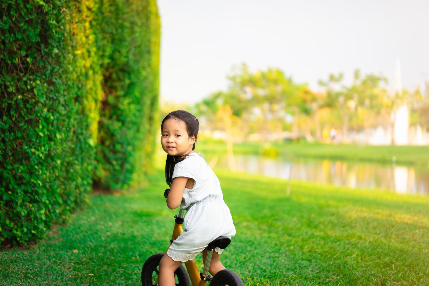 klein meisje loopfiets rijden in het park foto