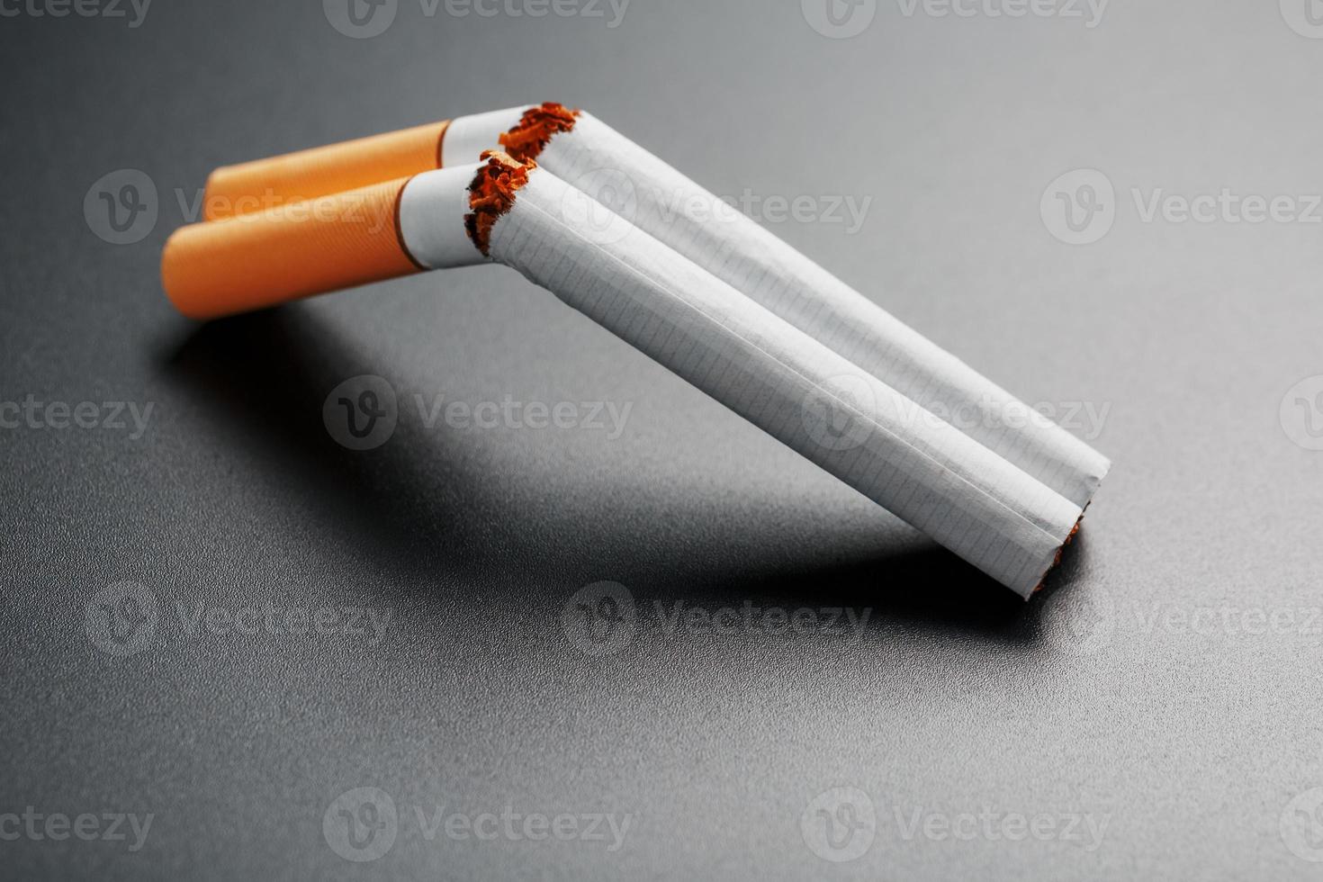 twee sigaretten in de het formulier van een dubbelloops jachtgeweer Aan een zwart achtergrond met kopiëren ruimte. hou op roken. de concept van roken doodt. foto