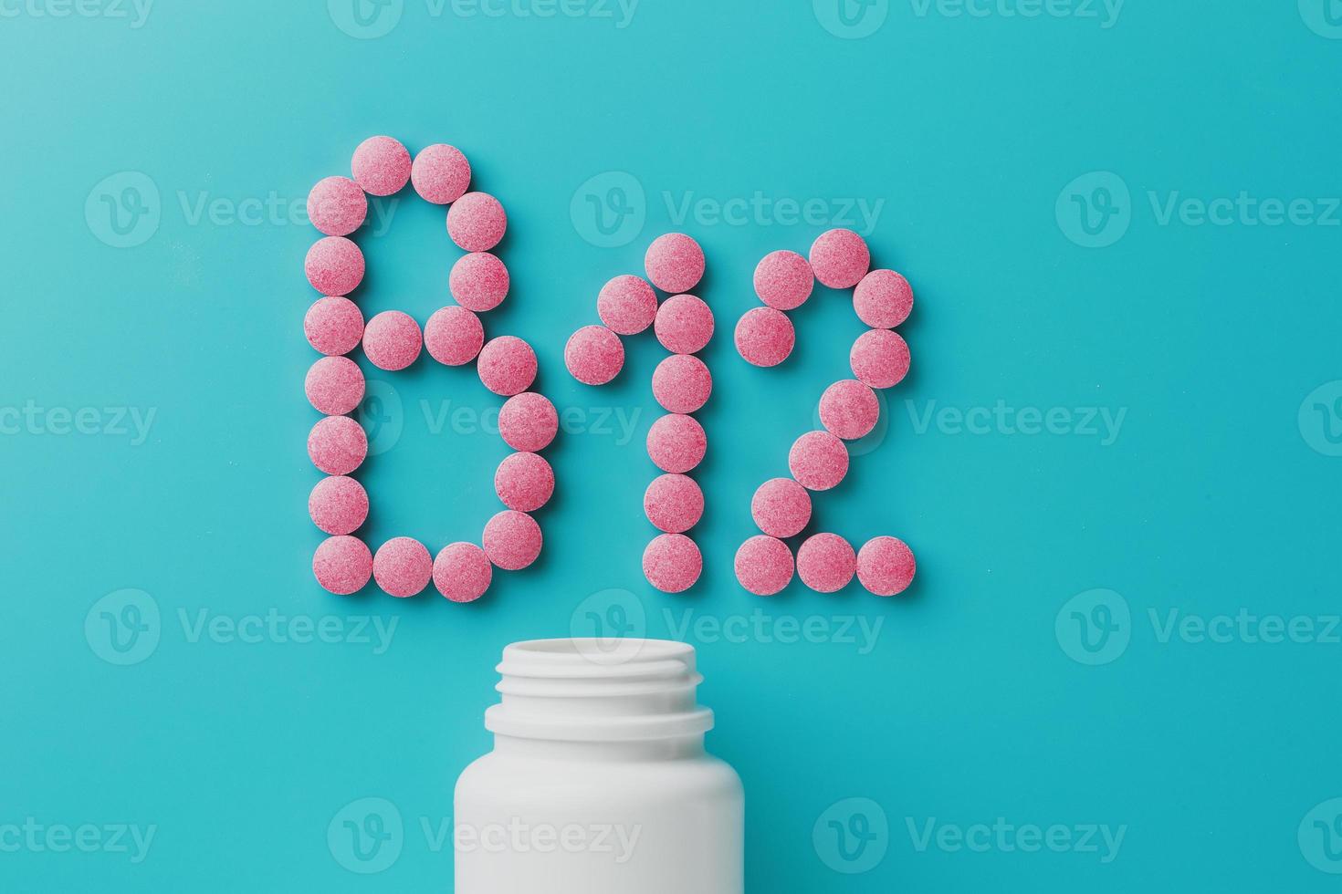 roze pillen in de vorm van de brief b12 Aan een blauw achtergrond, gemorst uit van een wit kan, laag contrast foto