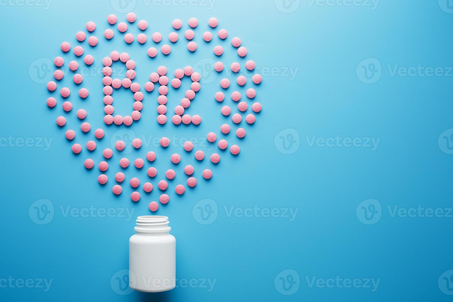 roze tablets in de het formulier van vitamines b12 in de hart Aan een blauw achtergrond, gemorst van een wit kan laag contrast foto