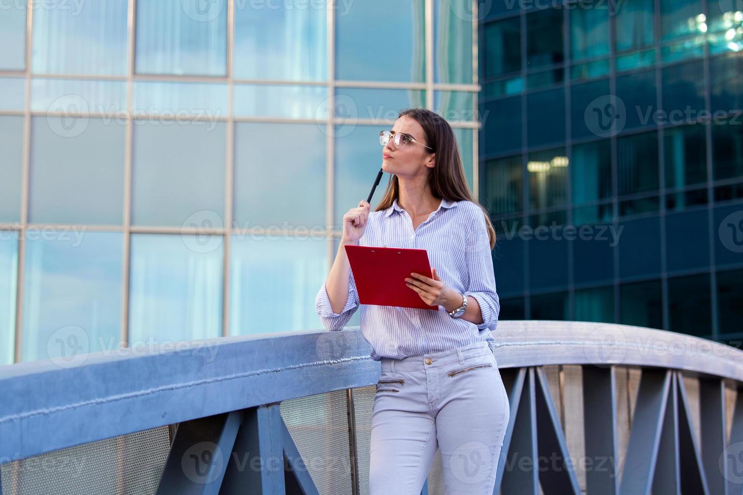 zakenvrouw in formeel slijtage denken over nieuw baan aanbod voordat ondertekening documenten. bedrijf vrouw Holding klembord. modern, hardwerkend vrouw Holding klem bord in handen, schrijven Aan documenten foto