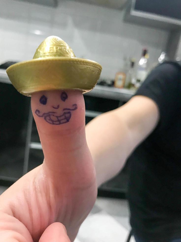 duim, vinger Mexicaans in goud hoed sombrero met geschilderd vrolijk vrolijk gezicht met snorren en ogen foto