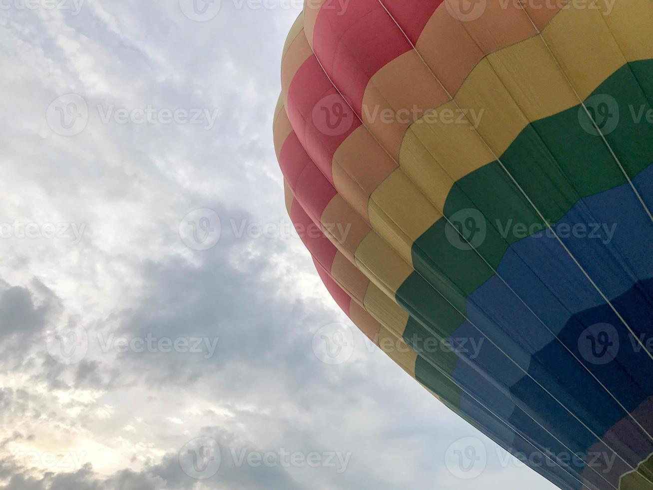 groot veelkleurig helder ronde regenboog gekleurde gestreept gestreept vliegend ballon met een mand tegen de lucht in de avond foto