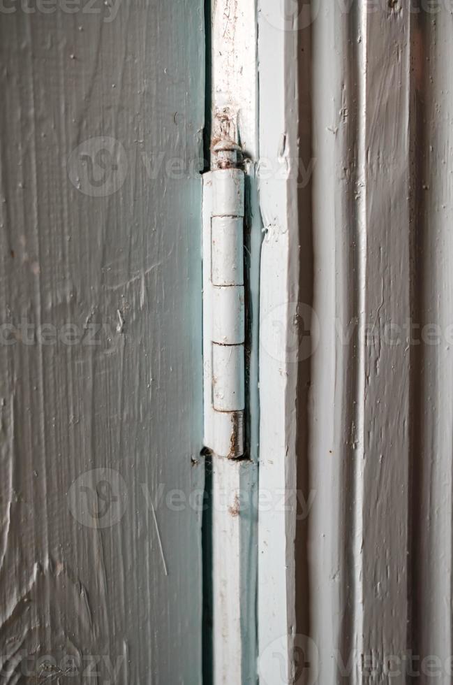 metaal scharnier Aan een houten geschilderd deur binnenshuis, in een landelijk huis. land stijl. foto