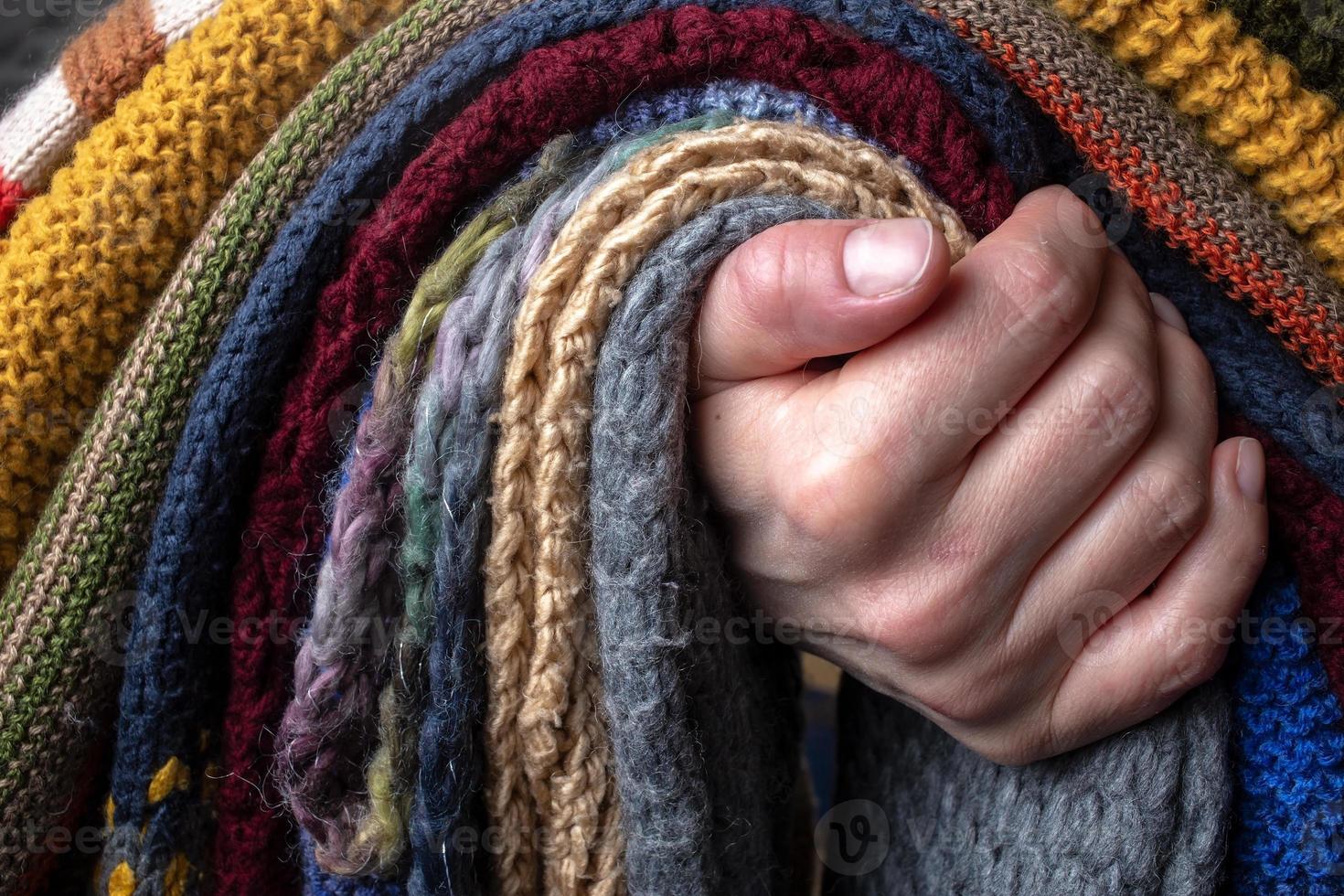 vrouw hand- Holding een reeks van gebreid sjaal, veelkleurig en met verschillend patronen. foto