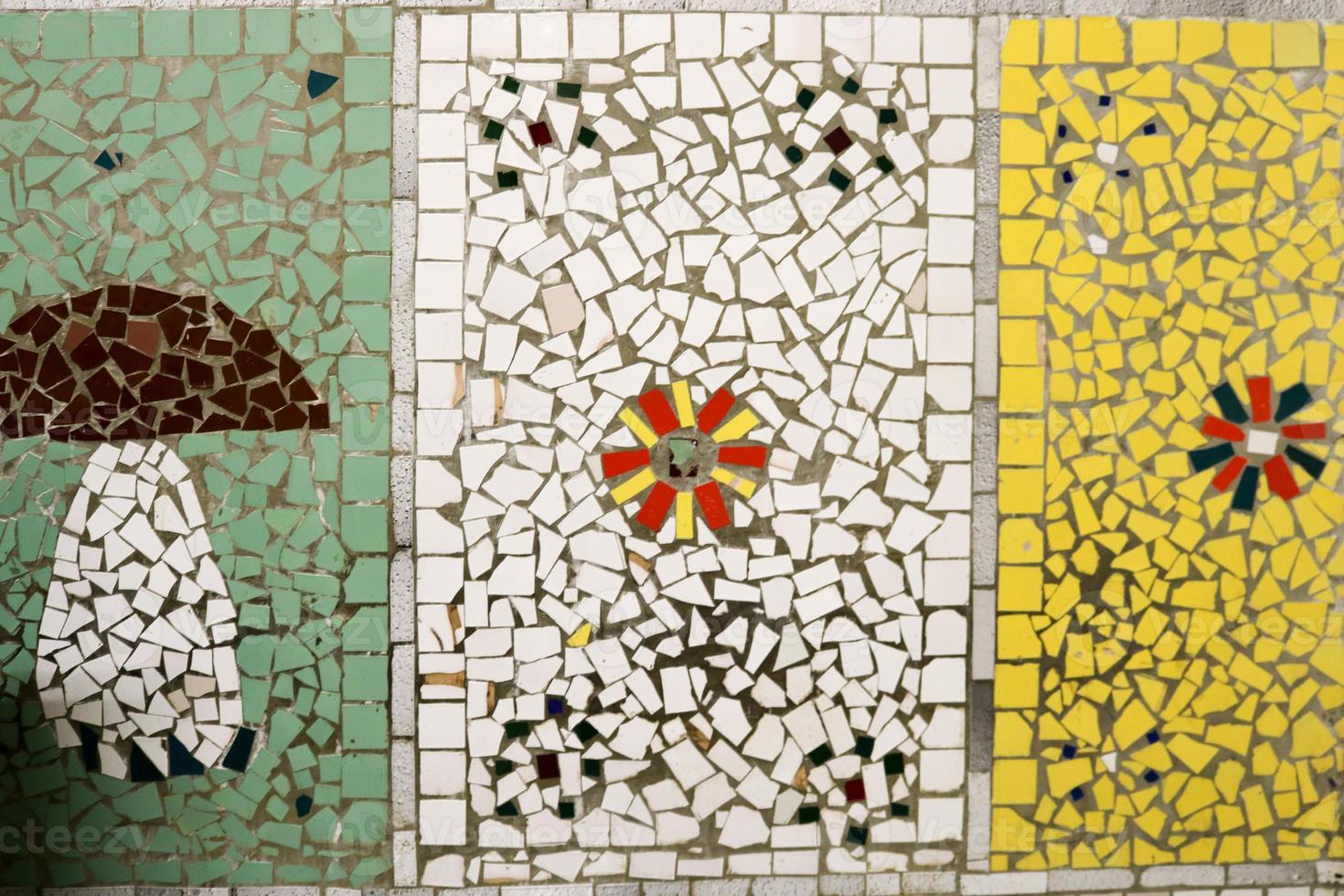 structuur van een keramisch mozaïek- van glas fragmenten van divers kleuren met een patroon van bloemen en een paddestoel. de achtergrond foto