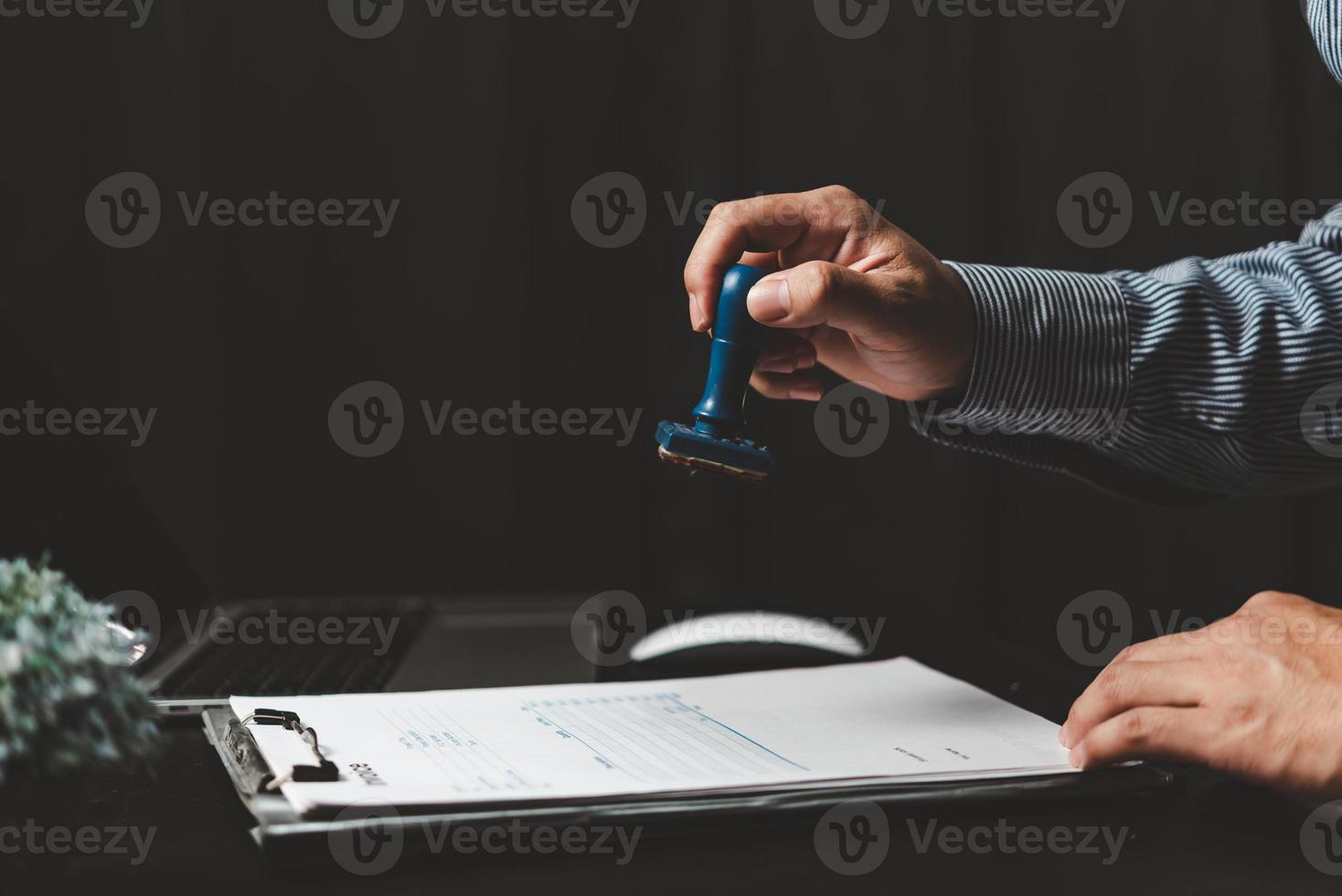 Mens stempelen goedkeuring van werk financiën bank of investering afzet documenten Aan bureau. foto