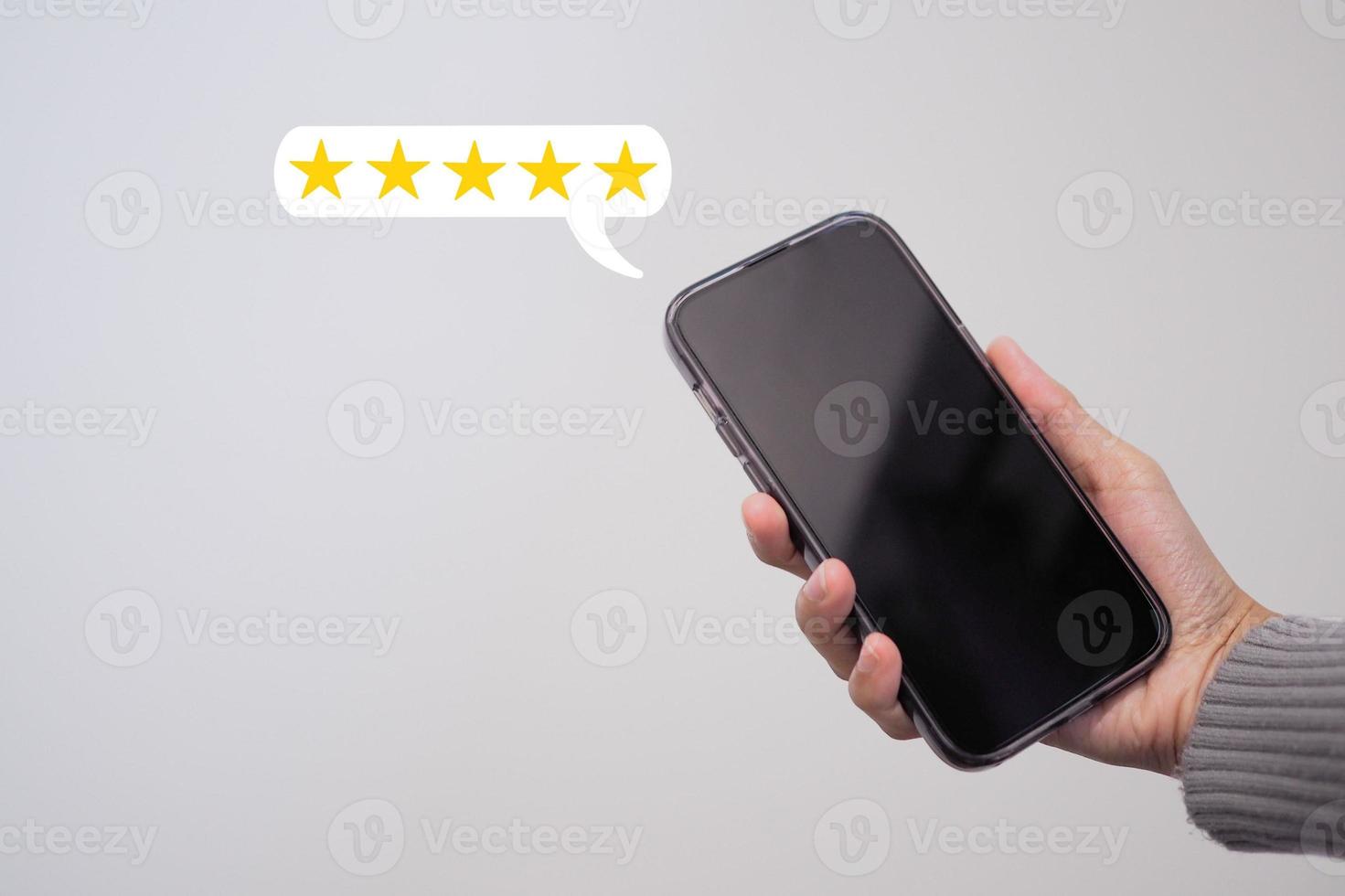 vrouw hand- gebruik makend van een smartphone met een vijf sterren pop-up icoon voor feedback, opnieuw bekijken, tevredenheid onderhoud. foto