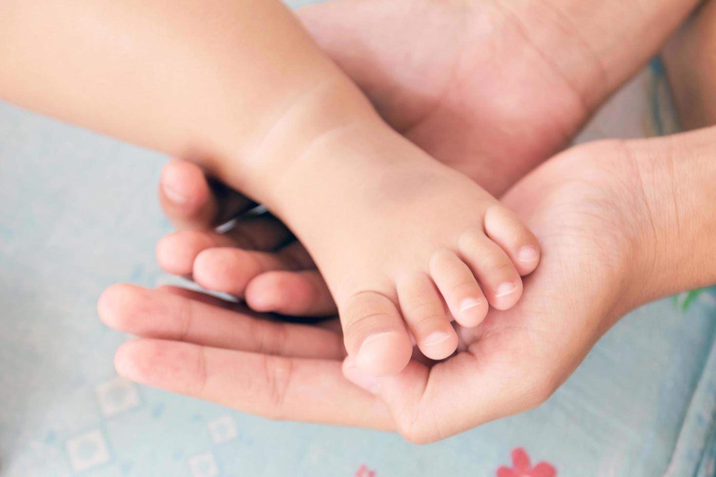 moeders hand wiegen de voet van een baby foto