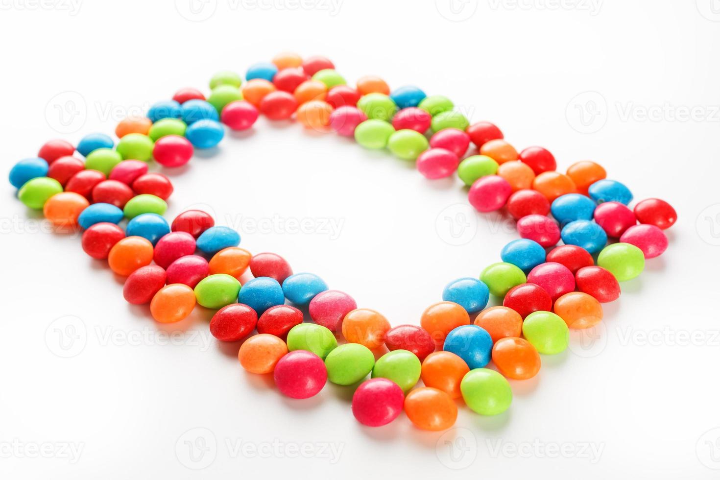 kader van veelkleurig snoepjes dichtbij omhoog. regenboog gekleurde dragee veelkleurig glazuur Aan een wit achtergrond foto