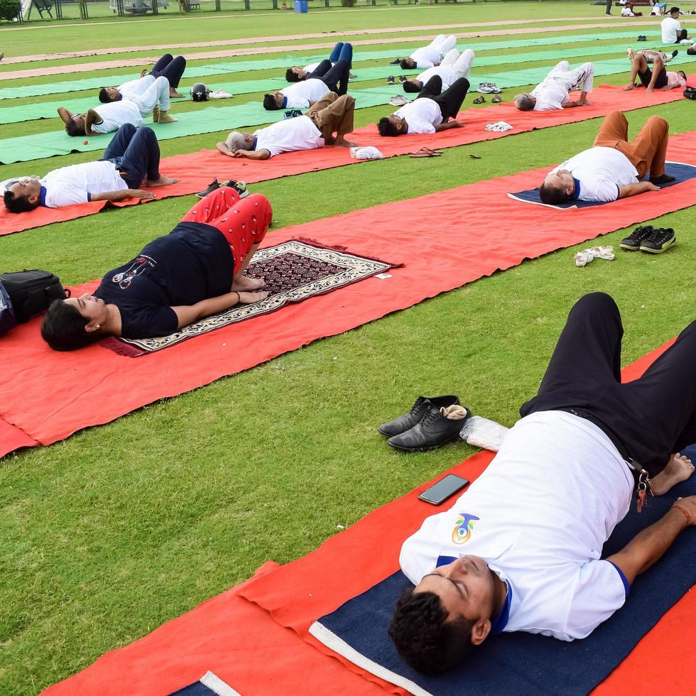 nieuw Delhi, Indië, juni 21 2022 - groep yoga oefening sessie voor mensen Bij Yamuna sport- complex in Delhi Aan Internationale yoga dag, groot groep van volwassenen Bijwonen yoga klasse in krekel stadion foto