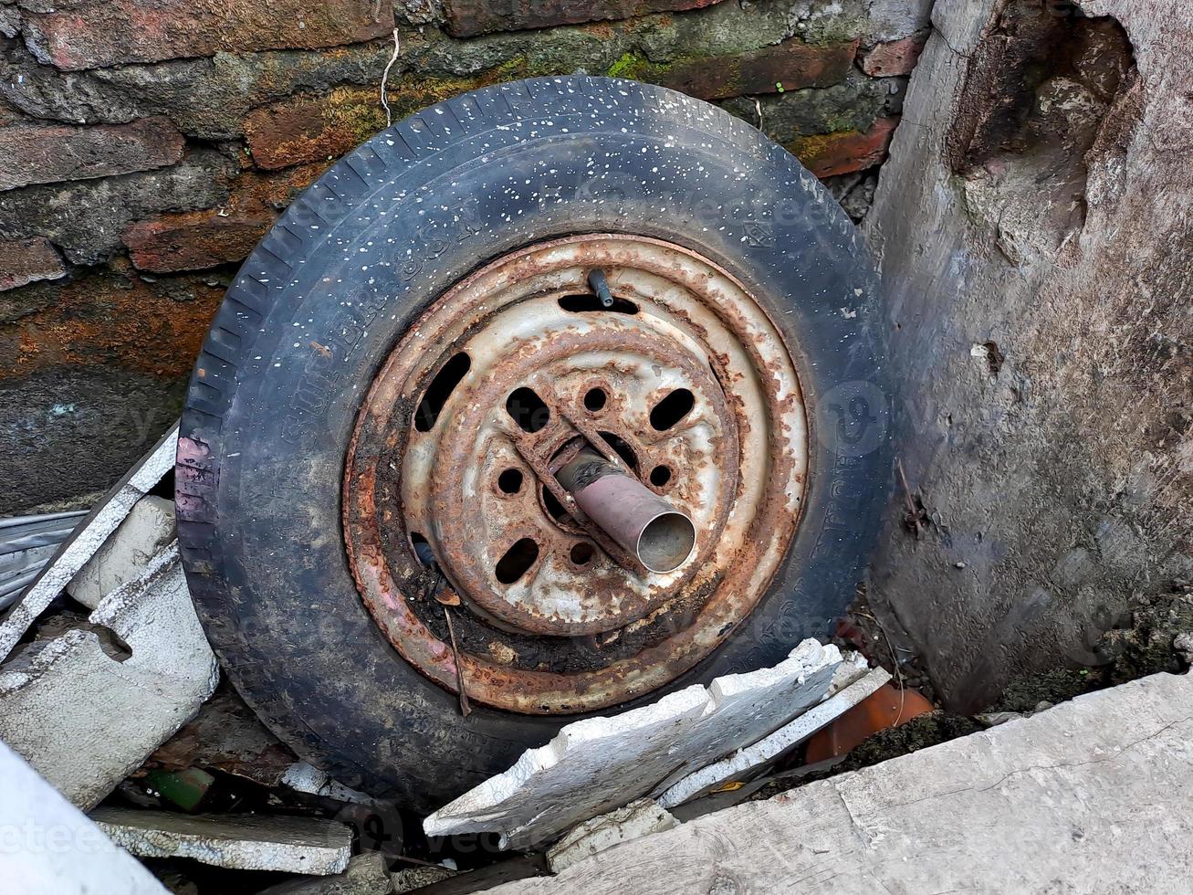 oud auto velgen, vlak en gebarsten, verroest door de steen muur. foto