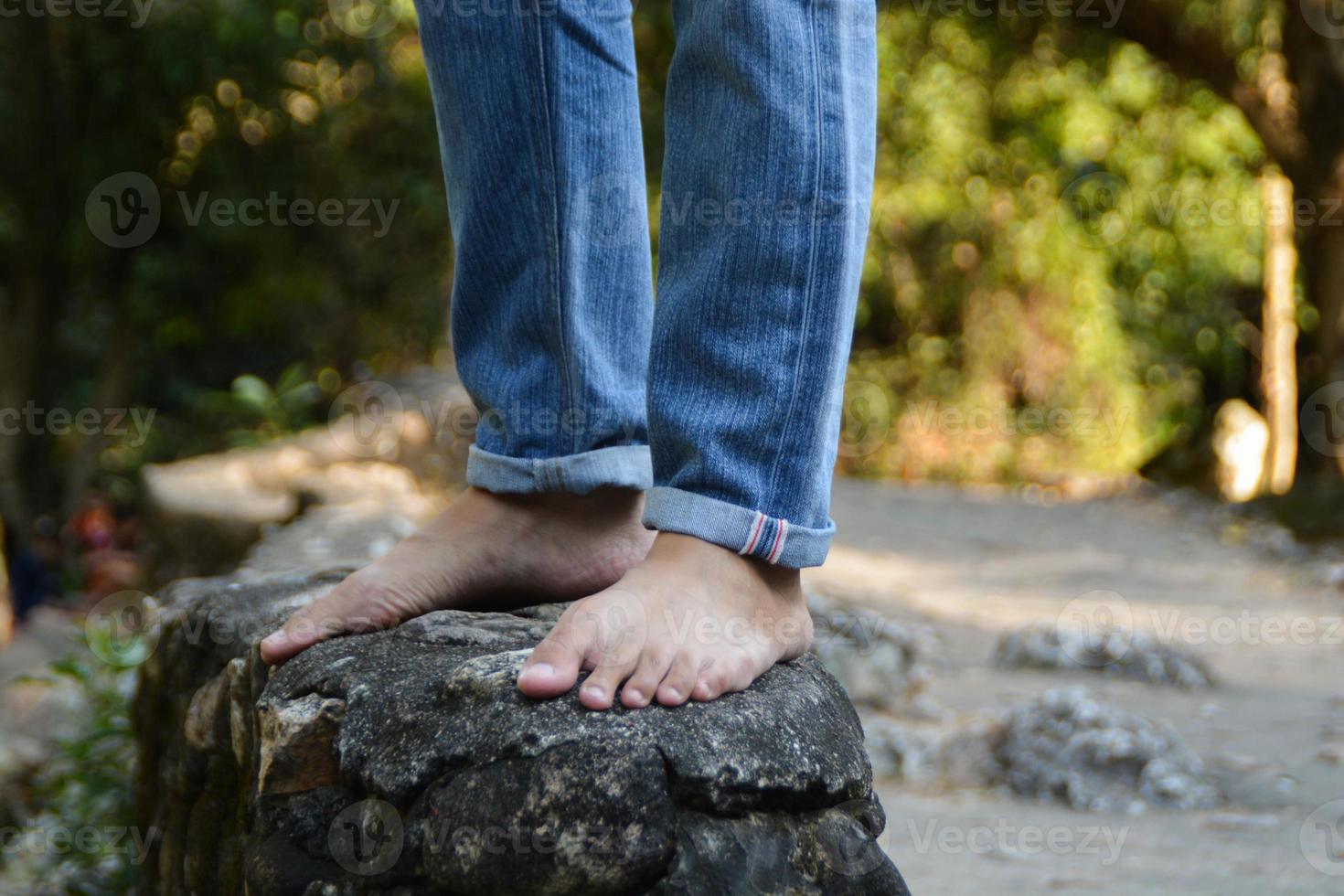 iemand vervelend jean en Nee schoenen staan Aan de rots Bij de waterval. foto