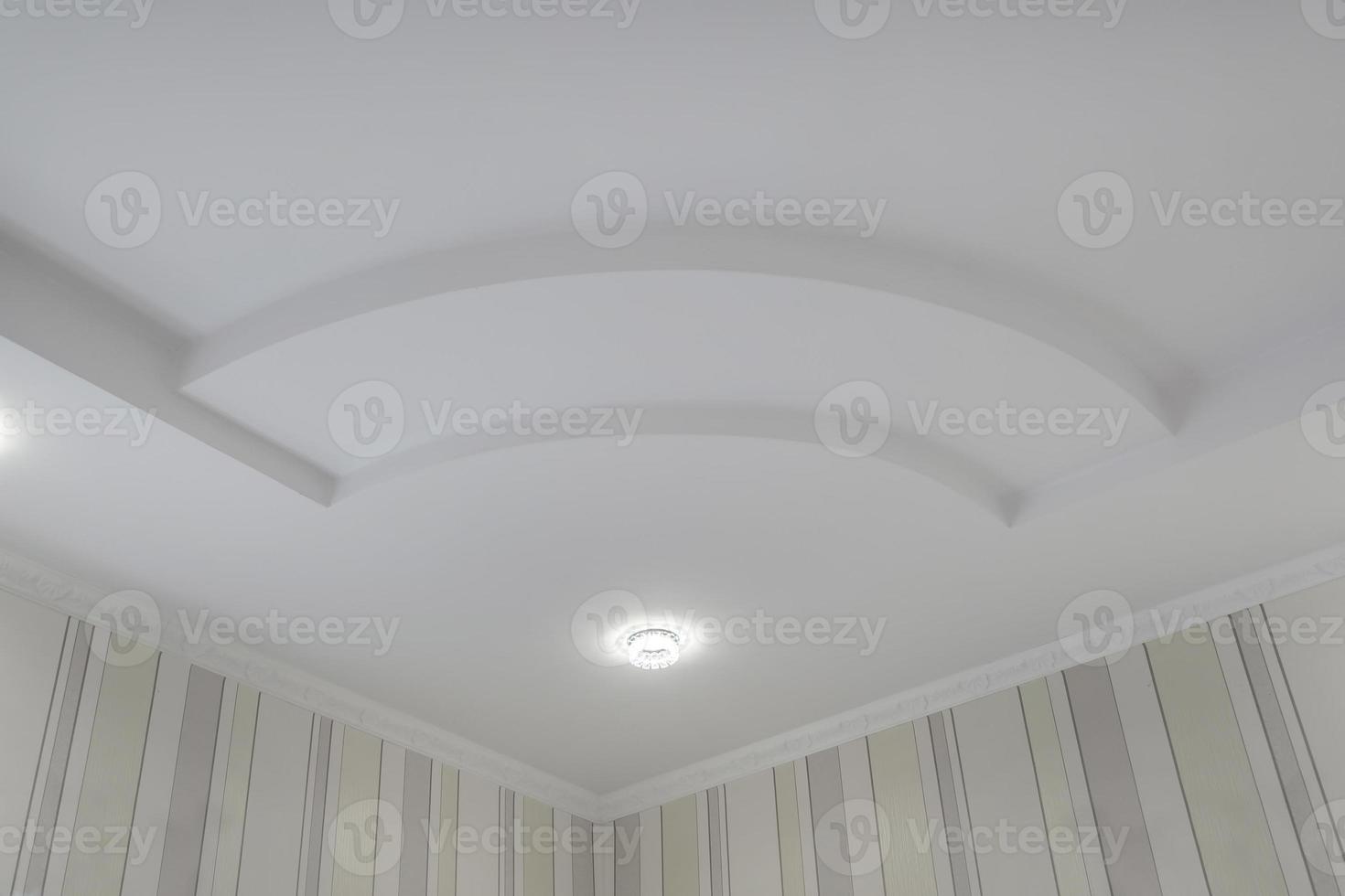 detail van hoek plafond met ingewikkeld kroon vormen. geschorst plafond en gipsplaat bouw in leeg kamer in appartement of huis. rekken plafond wit en complex vorm geven aan. foto