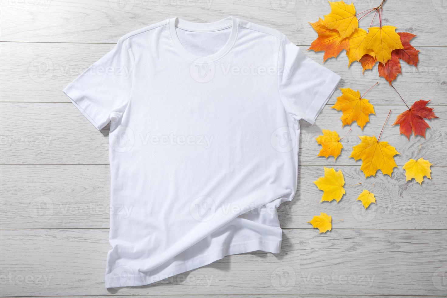 wit overhemd mockup - t-shirt met herfst bladeren Aan wit houten bureau foto