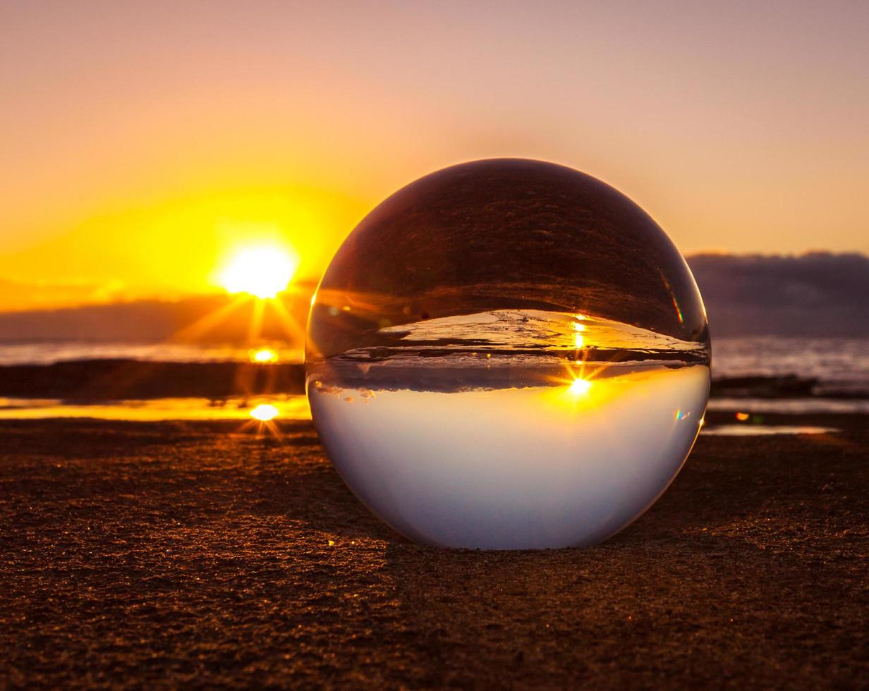 lensball op zand bij zonsondergang foto