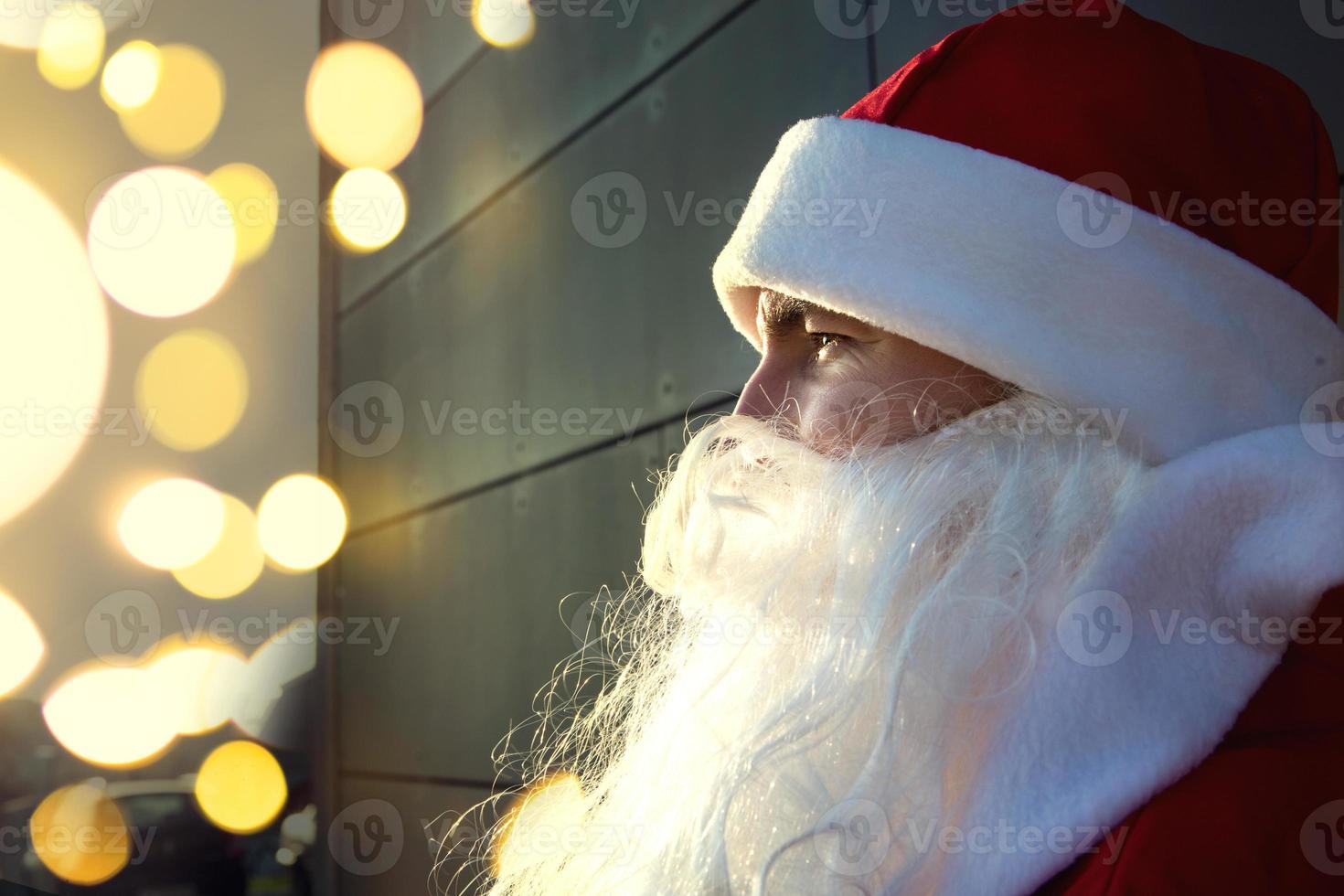 de kerstman claus gezicht detailopname Aan een grijs achtergrond. een fonkeling in zijn ogen, een wit baard, een rood pak met een hoed. kerstmis, nieuw jaar. Russisch opa vorst. grijs modern achtergrond, kopiëren ruimten foto