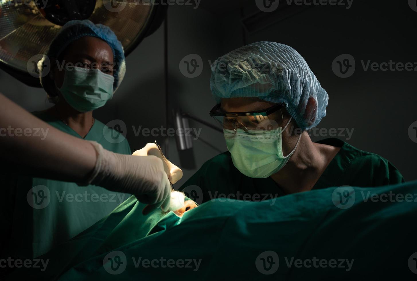 Aziatisch professioneel chirurgen team het uitvoeren van chirurgie in de in werking kamer, chirurg, assistenten, en verpleegsters het uitvoeren van chirurgie Aan een geduldig, Gezondheid zorg kanker en ziekte behandeling concept foto