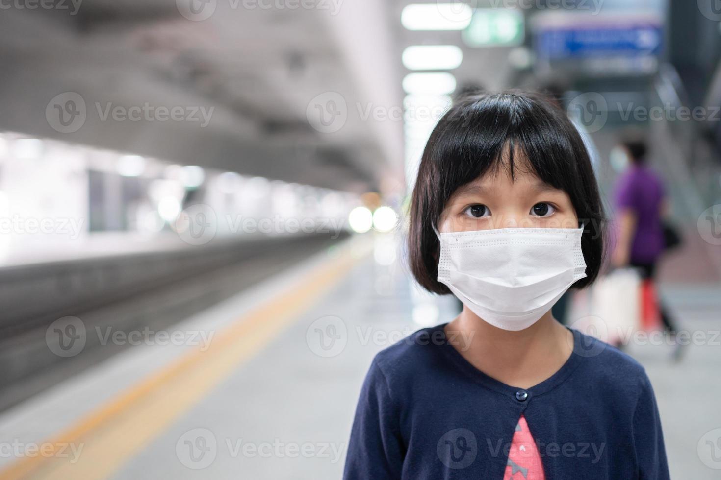 klein meisje met chirurgisch masker gezichtsbescherming griep en virusuitbraak in de skytrain of metro van het openbaar vervoer. concept van nieuwe normale levensstijl, met het openbaar vervoer om naar school te reizen. foto