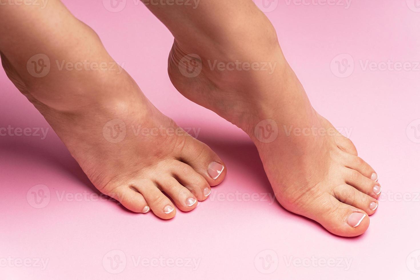 vrouw voeten met zacht huid en Frans pedicure Aan roze achtergrond foto