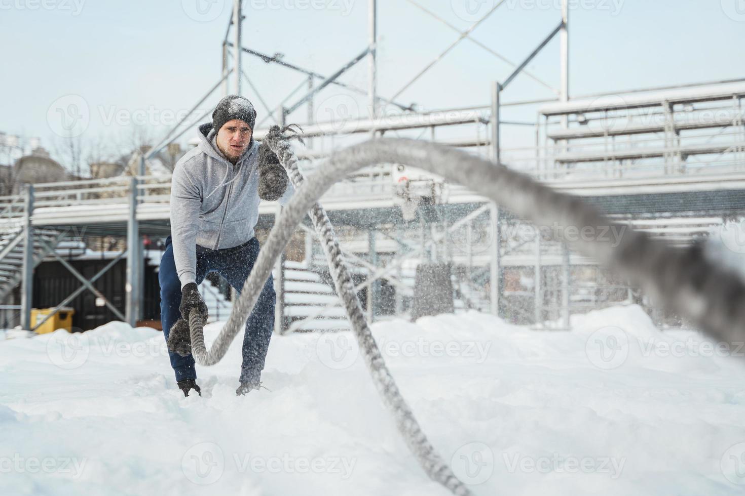 atleet werken uit met een strijd touwen gedurende besneeuwd winter dag foto